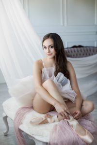 young woman who is a ballerina tying her shoe, boudoir photography