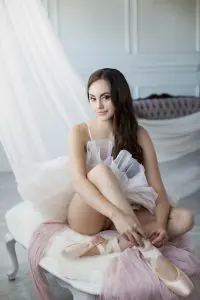 young woman who is a ballerina tying her shoe, boudoir photography