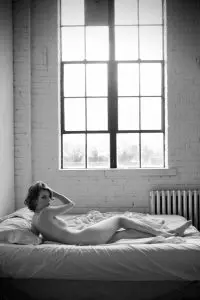 Contemporary black and white nude photography, casual lifestyle, laying on a bed